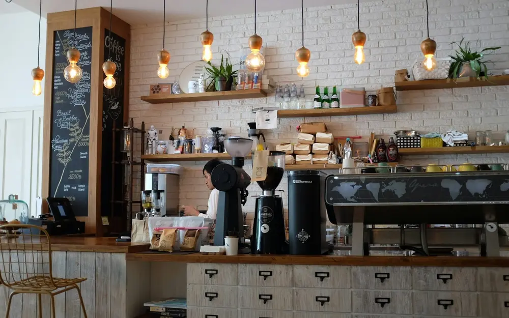 Heller Cafébereich mit Theke, Pendelleuchten und Holztischen