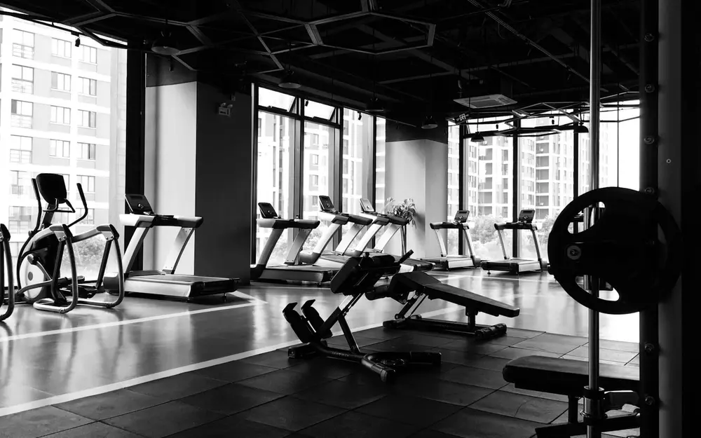 Fitnessstudio mit Trainingsgeräten und großen Fenstern